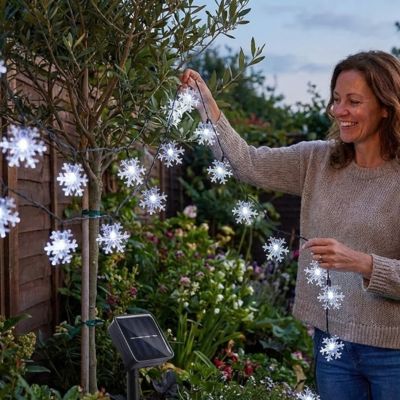 femme installe guirlande extérieur pour noël solaire flocons froid