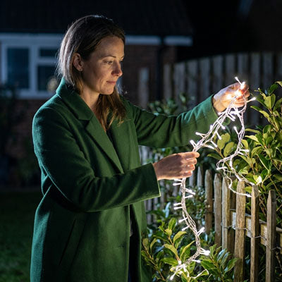 femme guirlande lumineuse solaire blanche dans mains jardin