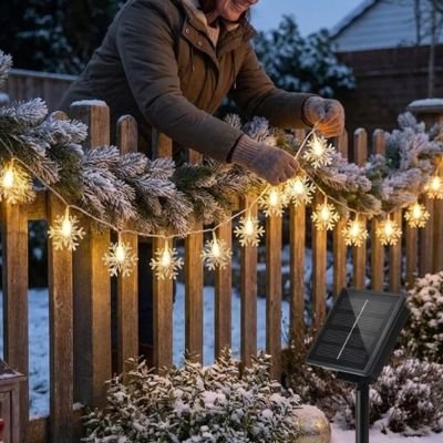 femme installe guirlande extérieur pour noël clôture hiver  