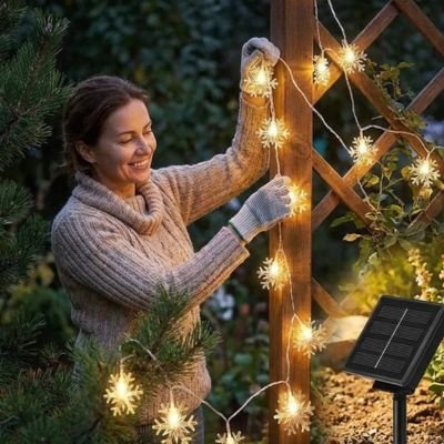 femme installe guirlande extérieur pour noël treillis jardin été
